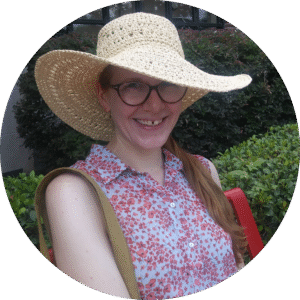JenHoyer_circle Photo of Jen in a straw hat and flowered blouse. Jen is a white woman who wears glasses.