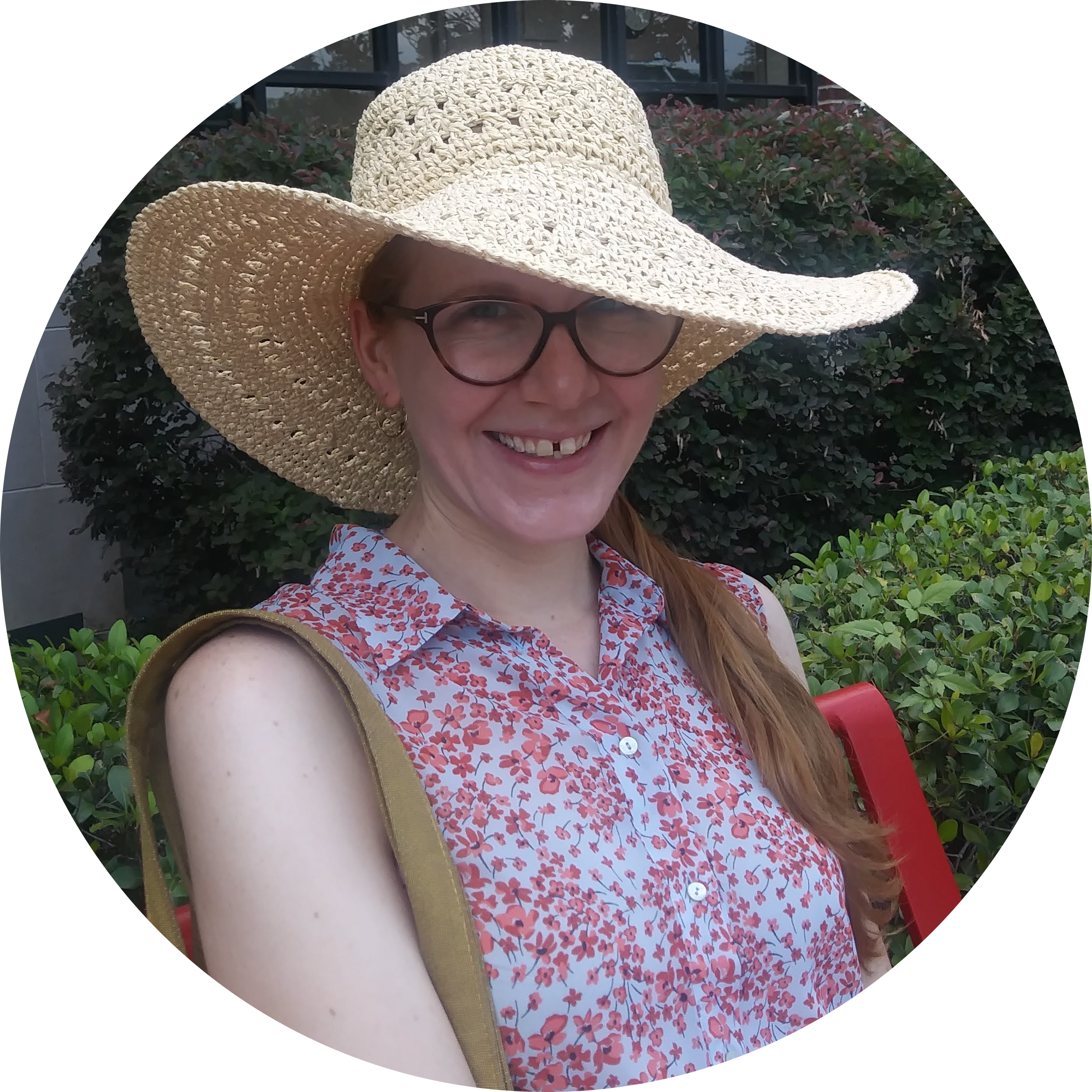 Photo of Jen in a straw hat and flowered blouse. Jen is a white woman who wears glasses.